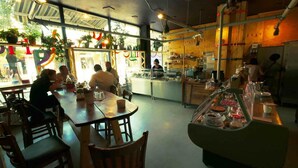 A restaurant with wooden tables and chairs, a counter with food display, and potted plants. - Hotel Alabin Central (Sofia)
