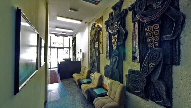 A hotel lobby with a reception desk, a seating area with sofas, and decorative wall art. - Hotel Alabin Central (Sofia)