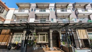 A multi-story residential building with balconies, a covered entrance, and a small garden area. - British Country Inn B&B (Luodong)