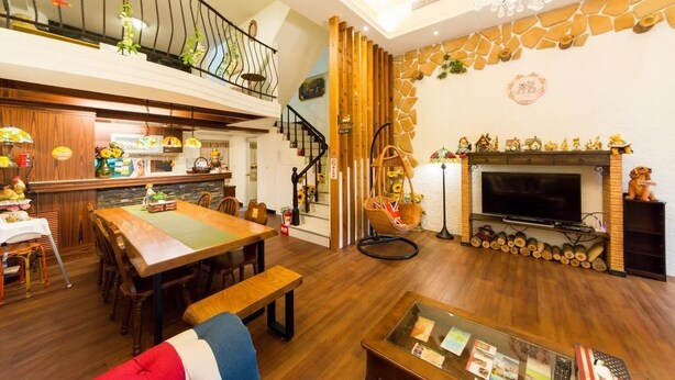 A spacious living room with a wooden dining table, a fireplace, and a television. - British Country Inn B&B (Luodong)