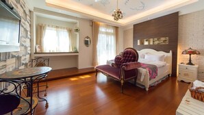 A bedroom with a bed, a vanity, a chandelier, and a dining table. - British Country Inn B&B (Luodong)