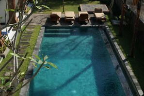Una piscina al aire libre, sillones reclinables de piscina