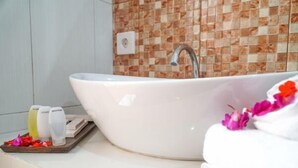 Ein Badezimmer mit einem weißen Waschbecken, einer gefliesten Rückwand und Pflegeprodukten auf einer Ablagefläche.