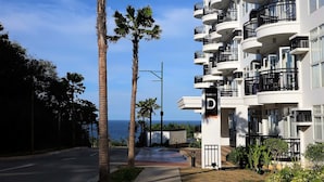 A modern hotel with multiple balconies, a clear view of the ocean, and a well-maintained garden area. - Gerbi's Condoplace at Oceanway Residences Boracay (Boracay Island)
