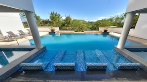 A modern outdoor pool with clear blue water, surrounded by lounge chairs and potted plants. - Gerbi's Condoplace at Oceanway Residences Boracay (Boracay Island)
