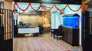 The entrance of Baga Fantasia Beach Inn with a Buddha statue, a desk, and a fish tank. - Baga Fantacia Beach Inn (Baga)