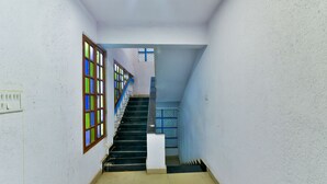 A staircase with a blue railing, a white wall, and a window with colorful panes. - Baga Fantacia Beach Inn (Baga)