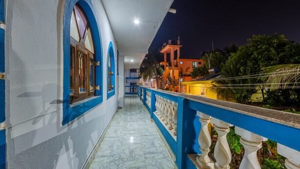 A corridor with blue and white walls, a marble floor, and a balcony with a railing. - Baga Fantacia Beach Inn (Baga)