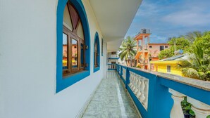 A corridor with blue and white walls, a marble floor, and a balcony with white balustrades. - Baga Fantacia Beach Inn (Baga)