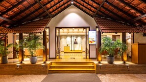 Fachada de un hotel con suelo de baldosas, una escalera de madera y plantas en macetas.