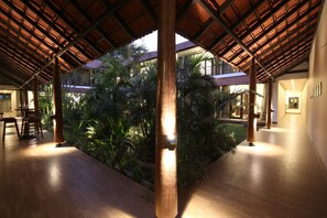 An indoor space with a wooden floor, a central column, and a covered area with plants. - Shiraz Boutique Hotel (Bhopal)