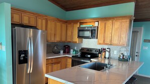 Una cocina moderna con armarios de madera, electrodomésticos de acero inoxidable, encimera de granito y una isla integrada con taburetes de bar.