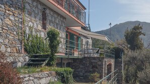 Een stenen gebouw met een balkon, een trap en een berg op de achtergrond.