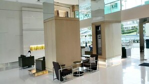 A spacious lobby with modern furniture, a glass ceiling, and a view of the outdoors.