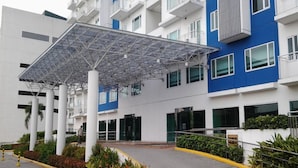 A modern building with a covered entrance, multiple floors, and balconies.