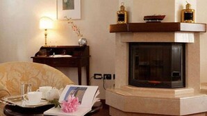 Une pièce confortable avec une cheminée, un bureau avec une lampe et un fauteuil.