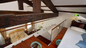 Une chambre aménagée en mezzanine avec un plafond en bois, un lit, un bureau et un miroir.