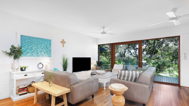 Una sala de estar moderna con un televisor de pantalla plana, dos sofás, una mesa de centro y piso de madera.