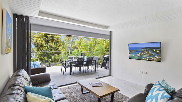 Una sala de estar moderna con un sofá de cuero, una mesa de centro y un televisor montado en la pared.