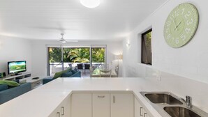 Cozinha moderna com uma ilha grande, armários brancos e um relógio verde na parede.