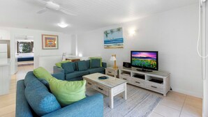 Uma sala de estar moderna com sofá, mesa de centro, televisão e obras de arte na parede.