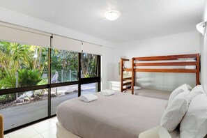 A bedroom with a large window, a bunk bed, and a bedside table. - Tea Trees (Noosa Heads)