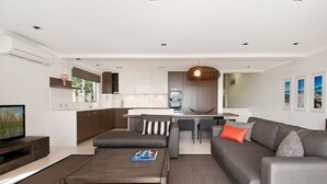 A modern living room with a sofa, coffee table, and TV. - Outlook (Noosa Heads)