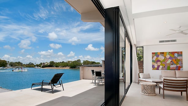 A modern outdoor patio with a view of a body of water, a boat, and a colorful abstract painting. - Weyba Quays (Noosa Heads)