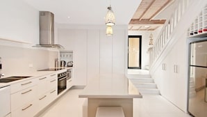 A modern kitchen with white cabinetry, stainless steel appliances, and a central island. - Weyba Quays (Noosa Heads)