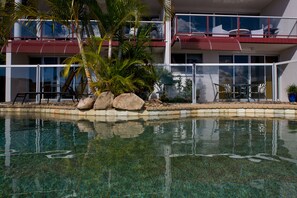 A pool with clear water, surrounded by rocks and palm trees. - Anchorage (Noosaville)