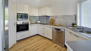 Eine moderne Küche mit weißen Schränken, einem Edelstahl-Kühlschrank, einem Backofen, einem Toaster, einem Geschirrspüler und einer Arbeitsplatte aus Granit.