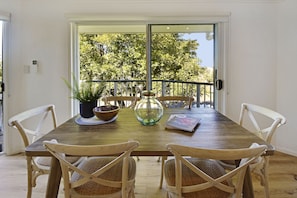 Une table de salle à manger en bois, avec quatre chaises, une plante en pot, un bol et un pichet en verre.