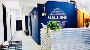 Un espace d’accueil moderne avec un mur bleu, un panneau d’accueil et un ventilateur de plafond.