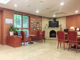 Un comedor con chimenea de ladrillo, televisor y una mesa con sillas.