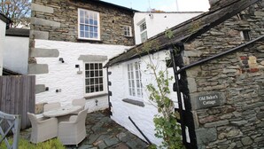 A stone cottage with a sign reading "Old Baker's Cottage." - Old Bakers Cottage, ground floor centrally located cottage in the heart of Grasmere. (Ambleside)
