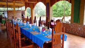 A long dining table set with blue tablecloths, wooden chairs, and various table settings. - Emerald Lodge Turmi (Turmi)