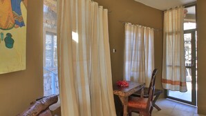 A room with a wooden table and chairs, beige curtains, and a large painting on the wall. - Emerald Lodge Turmi (Turmi)