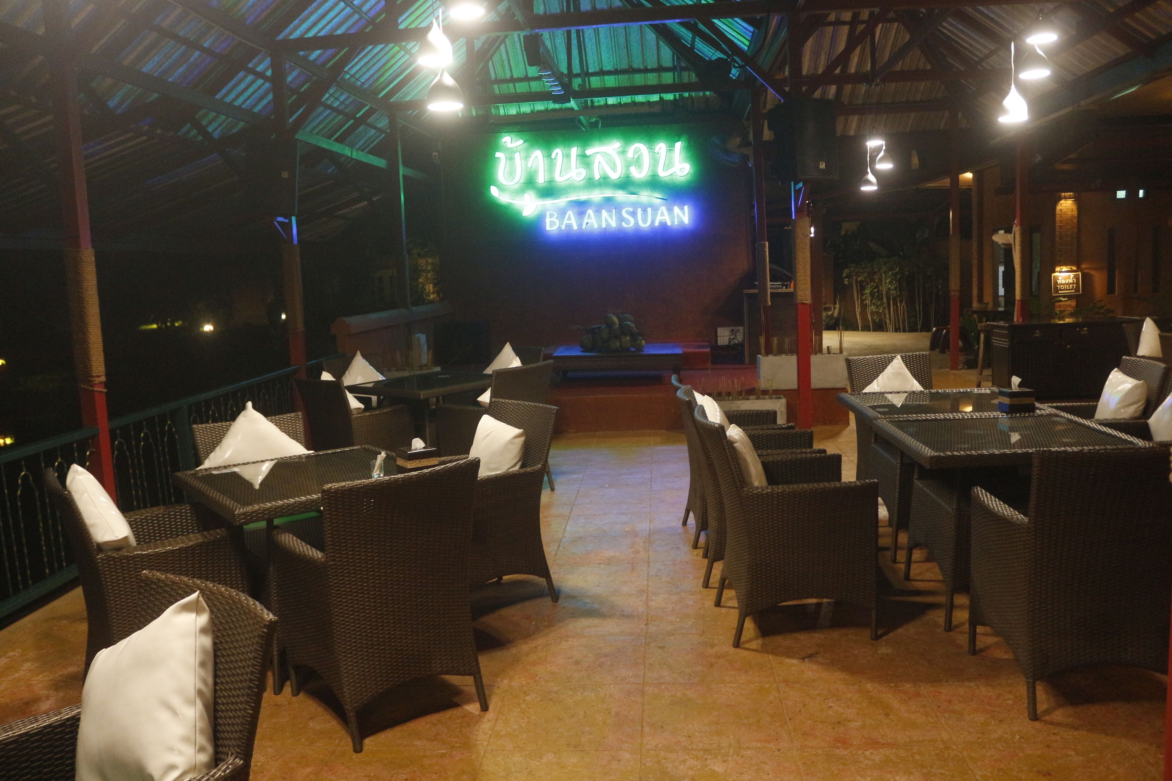 A restaurant with wicker furniture and a neon sign.