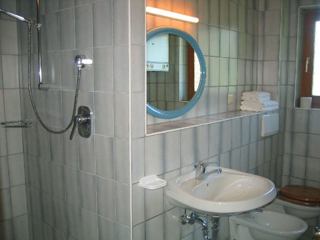 Ein Badezimmer mit Dusche, Waschbecken, Toilette und Spiegel.