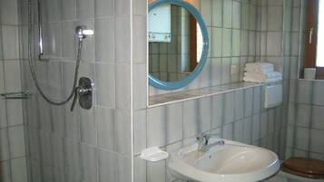 Ein Badezimmer mit Dusche, Waschbecken, Toilette und Spiegel.