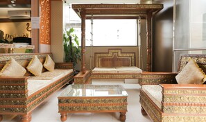 Una habitación tradicional con muebles ornamentados, incluyendo una cama con dosel y sofás a juego, además de una mesa de centro de vidrio.