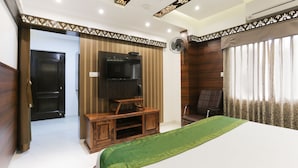 A bedroom with a bed, a TV, a wooden cabinet, a chair, and a fan. - Treebo Trend Dvaraka Inn (Bengaluru)