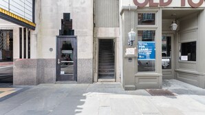 Un edificio con un cartello 'Retail for Lease', una porta e una scala che conduce a un piano superiore.