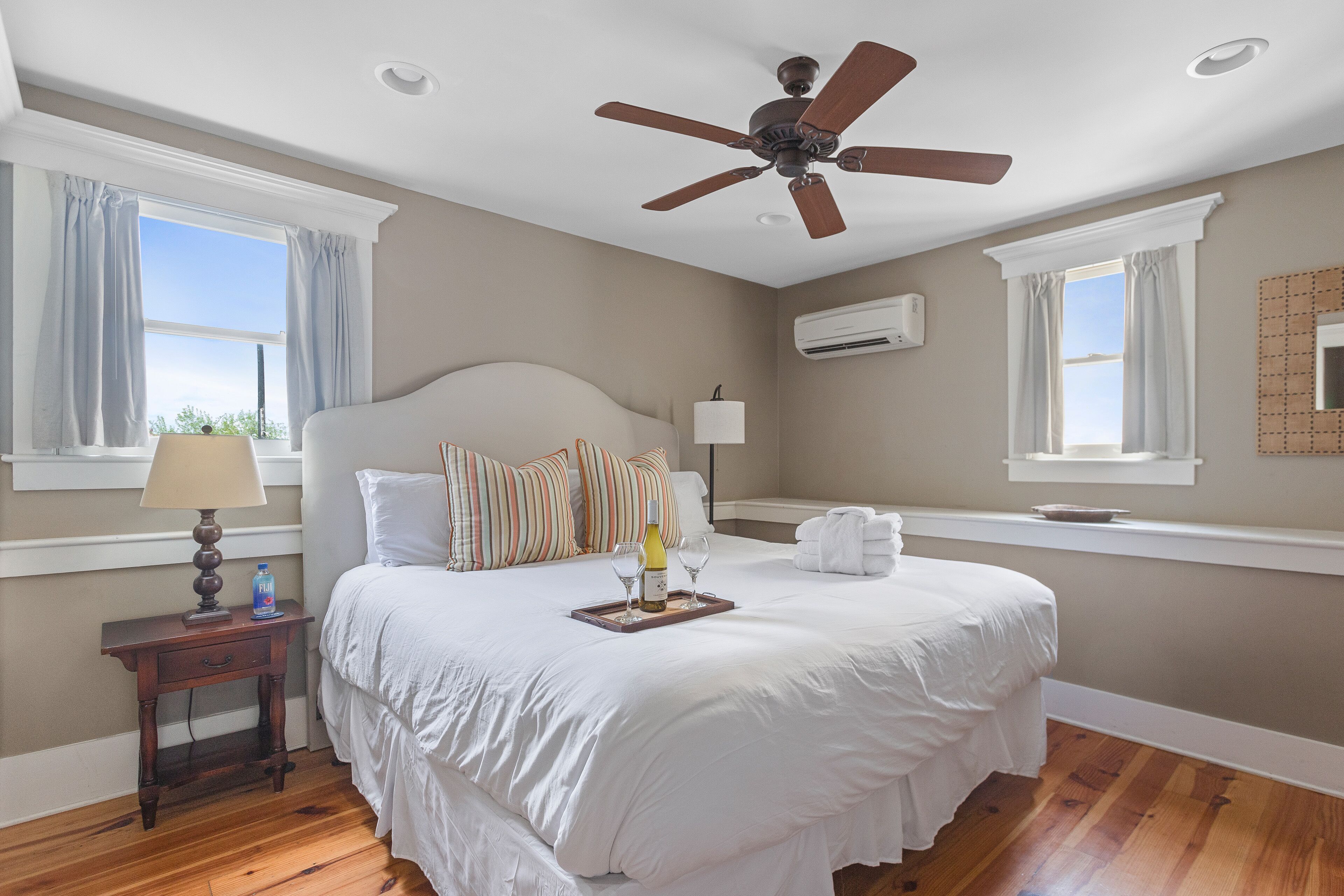 A bedroom with a large bed, a ceiling fan, and a window with curtains.