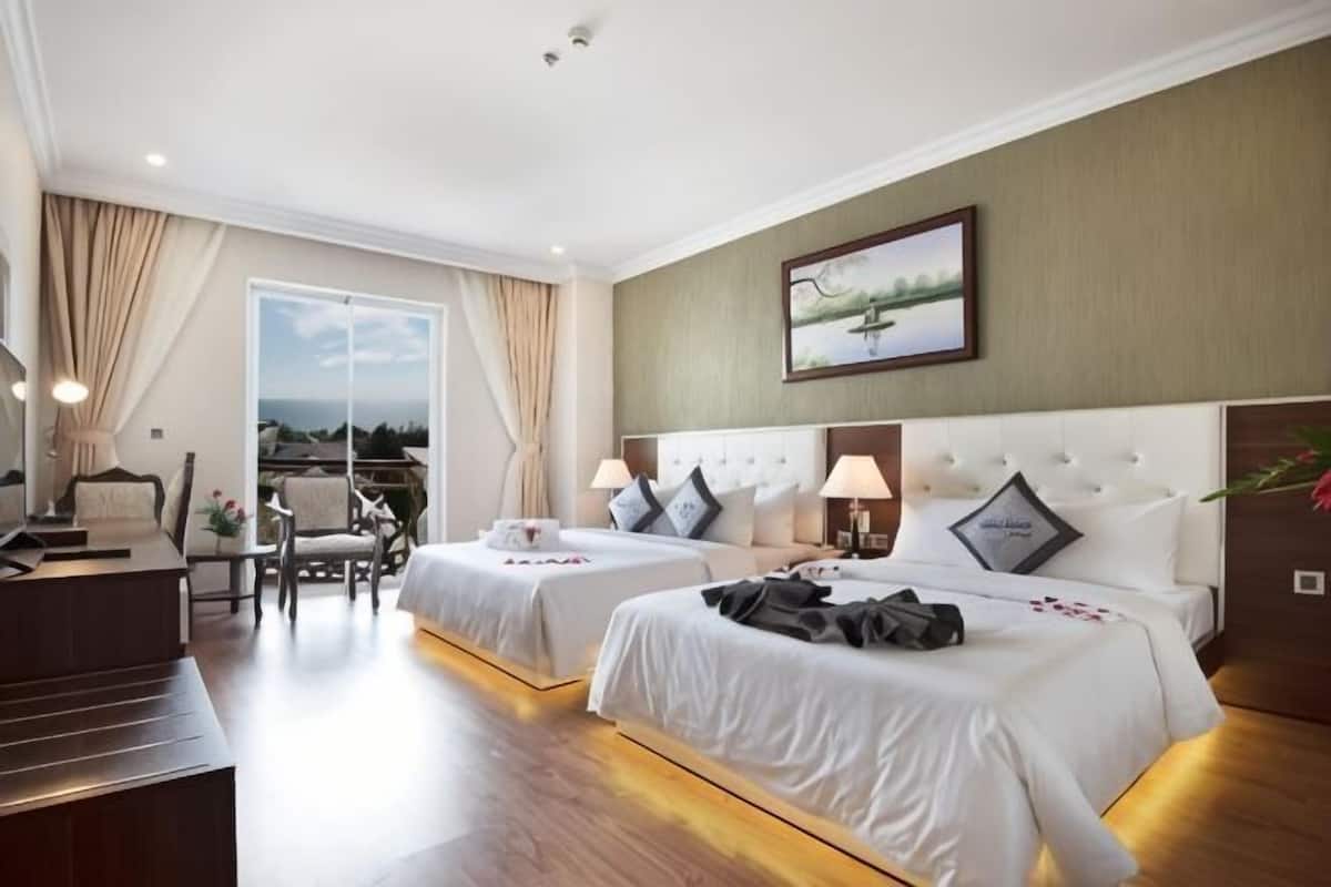 A hotel room with two beds, a desk, a chair, and a large window with a view.