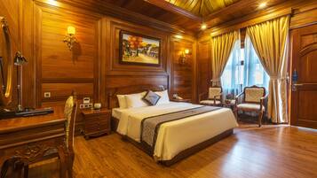 A wooden-paneled bedroom with a large bed, two bedside tables, a desk, and a chair.