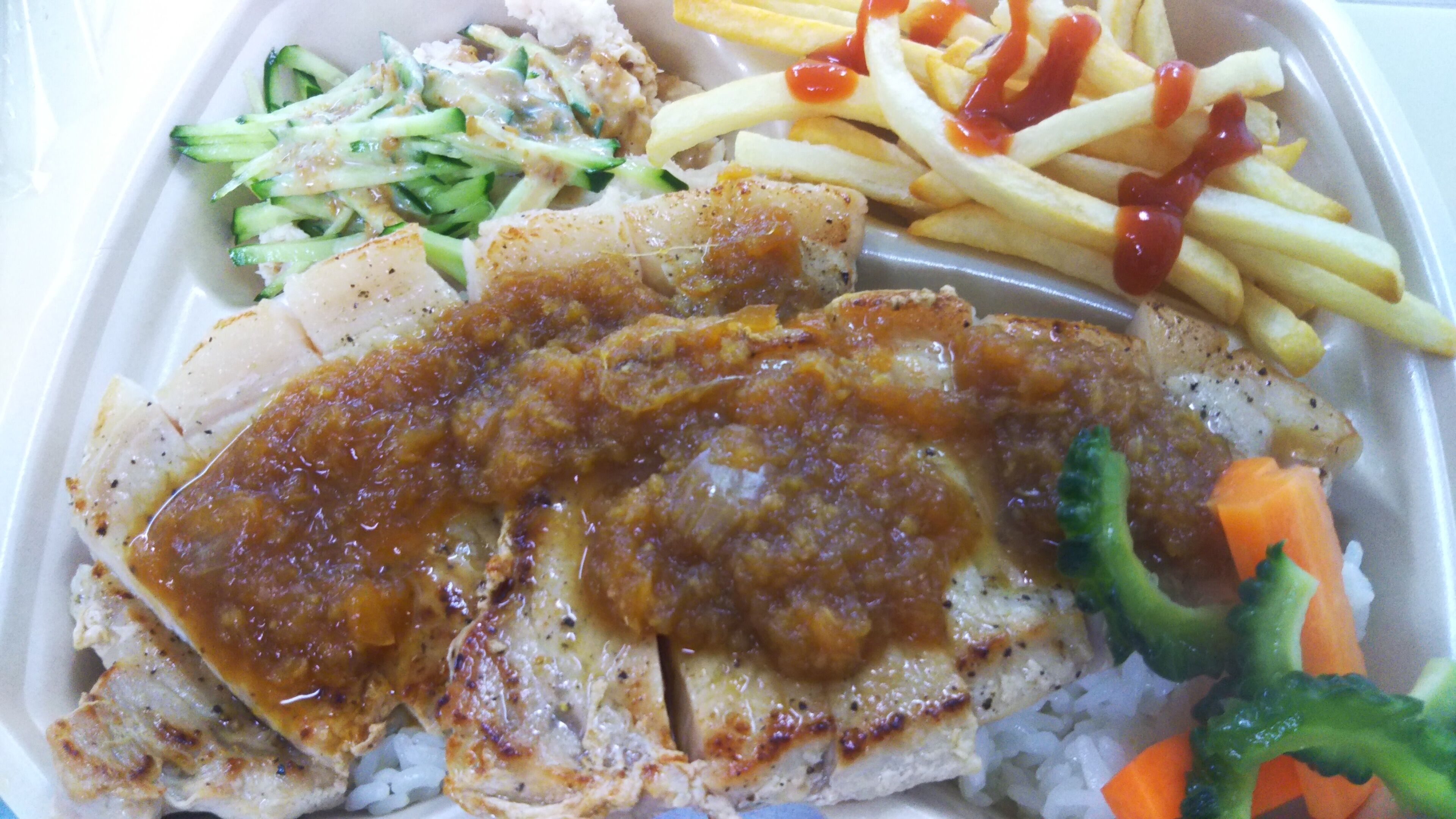 Un plato con pollo a la parrilla, papas fritas, ensalada de col y arroz con verduras.