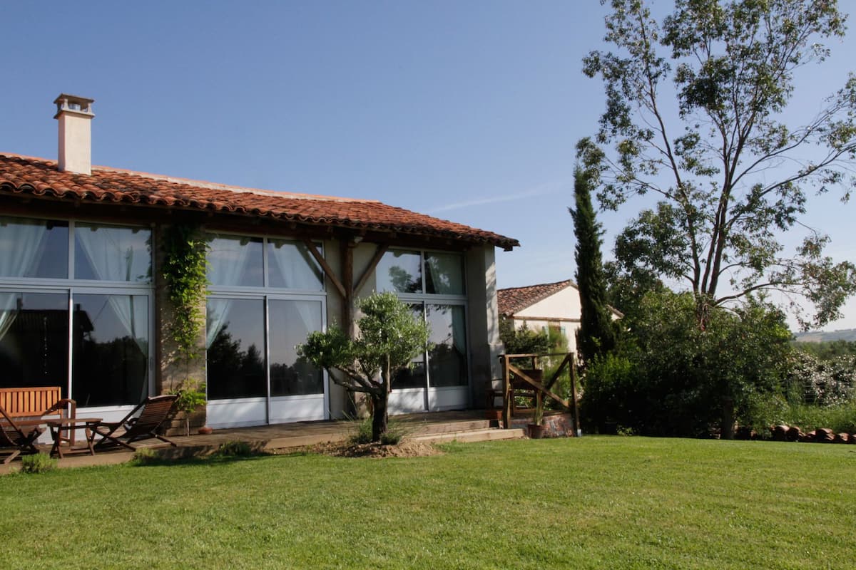 A house with a tiled roof, large windows, and a grassy lawn.