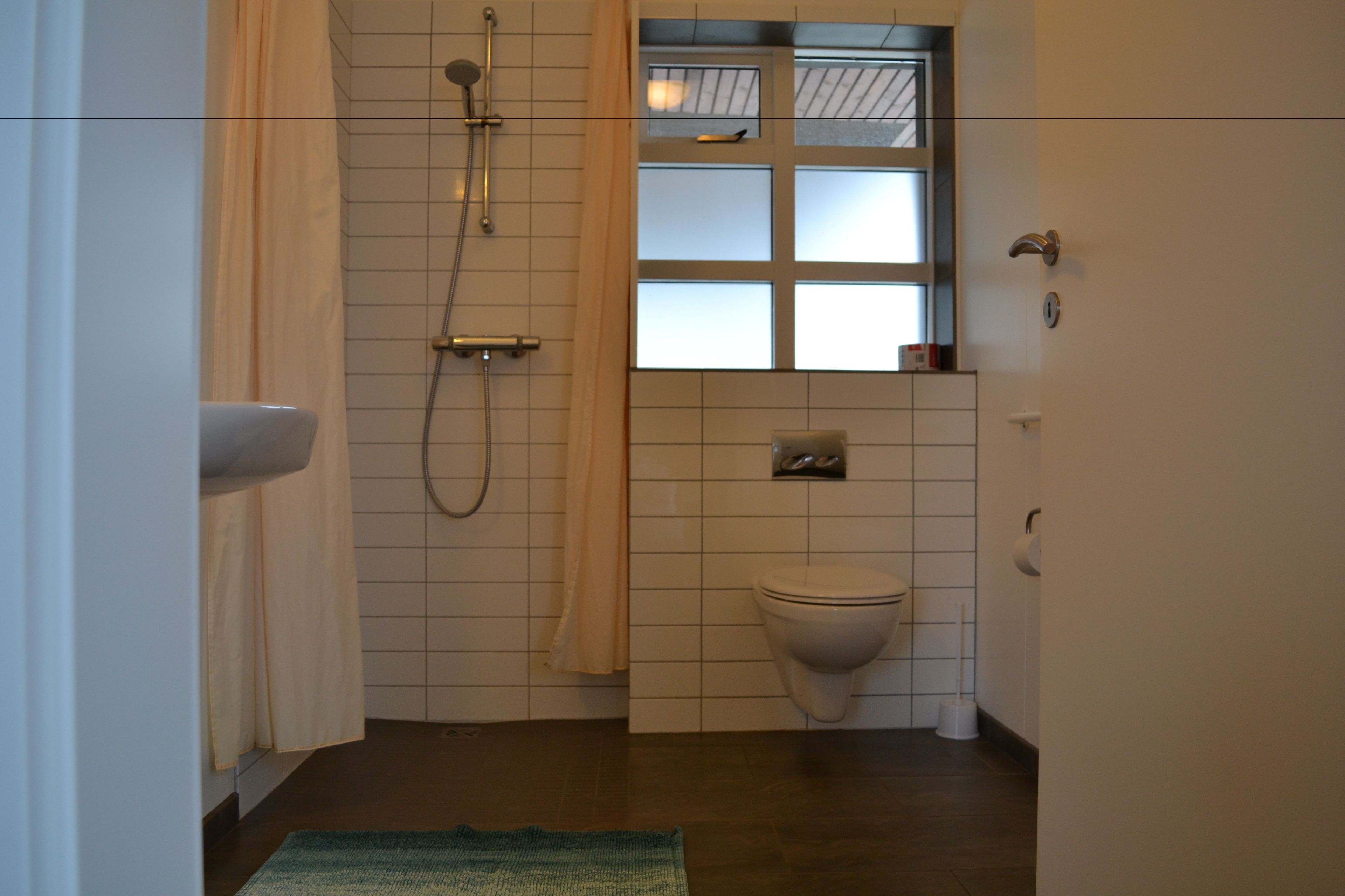 Kylpyhuone, jossa on suihku, wc ja ikkuna.