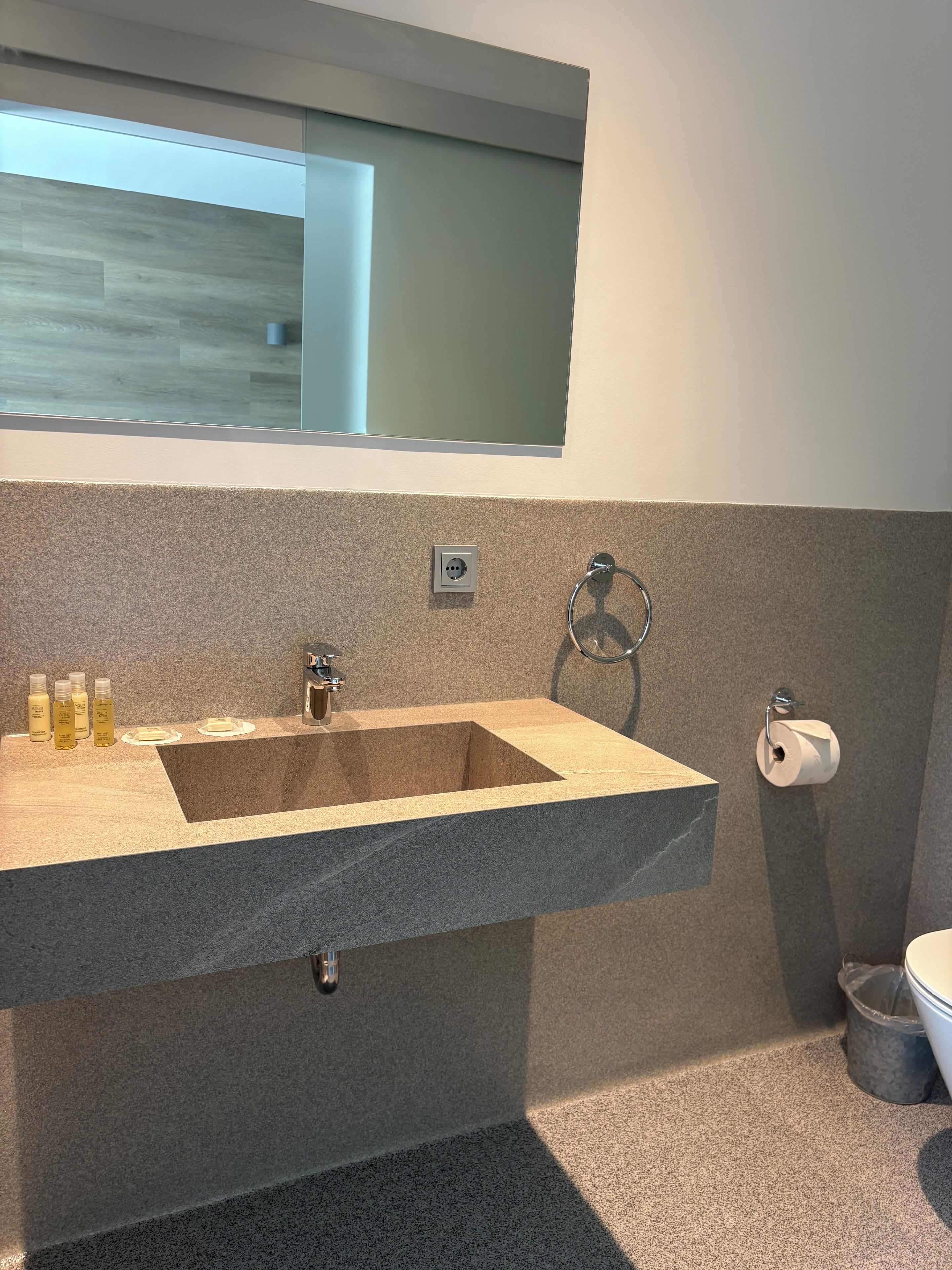 A bathroom with a built-in sink, a mirror above it, and a toilet.